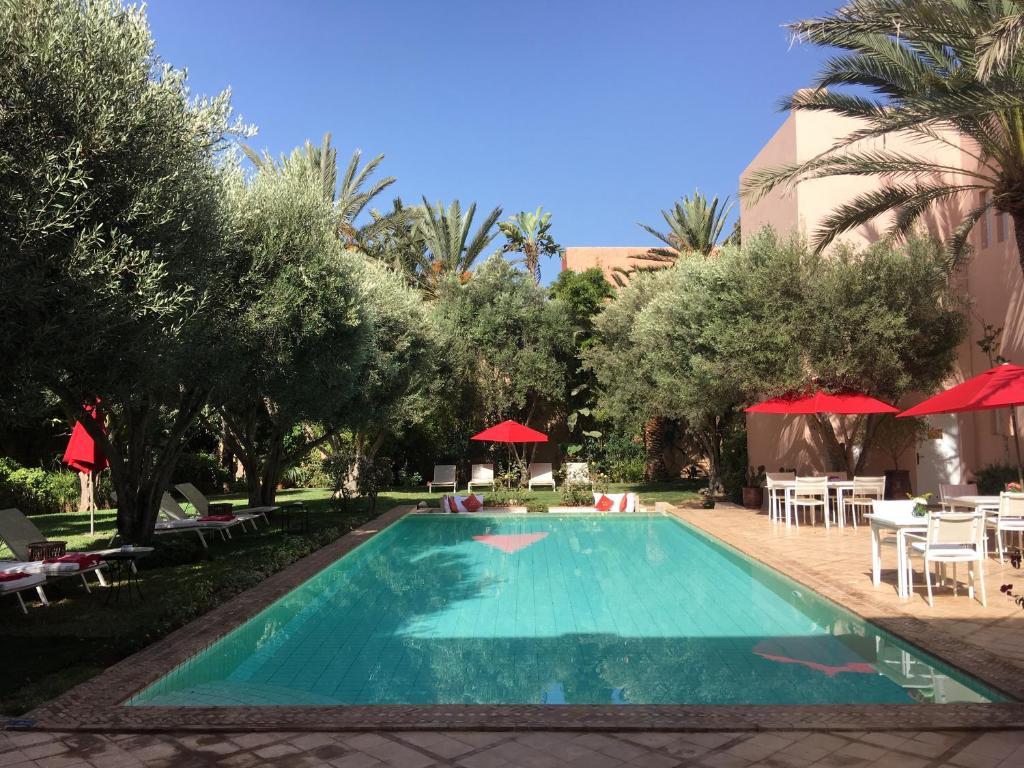 einen Pool mit Sonnenschirmen, Tischen und Stühlen in der Unterkunft Riad des Golfs in Agadir