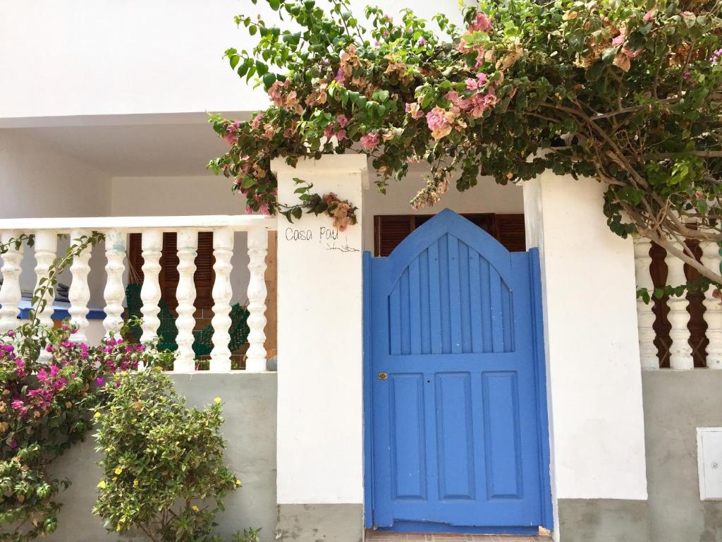 a blue door in a white house with flowers at Casa Pau in Santa Maria