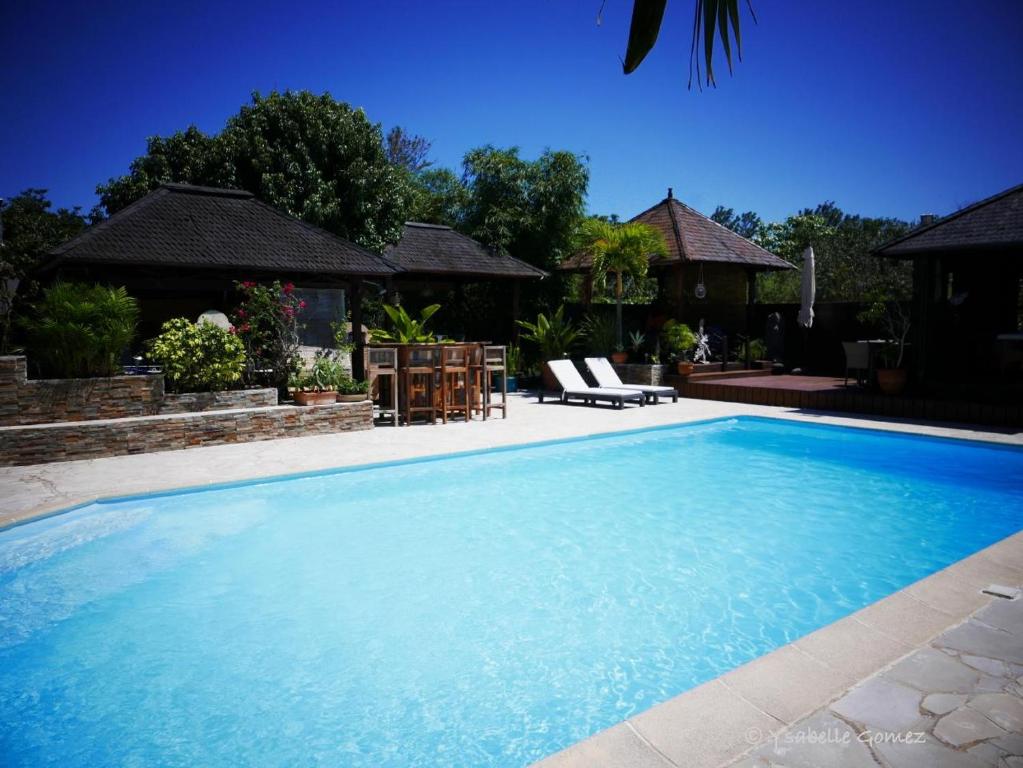 a large blue swimming pool with two chairs in a yard at Lotus Garden - Île de la Réunion in Ravine des Cabris