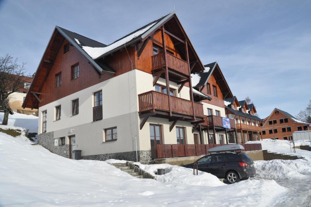 Roudnice的住宿－Apartmán Vítkovice，雪地里停着汽车的建筑物