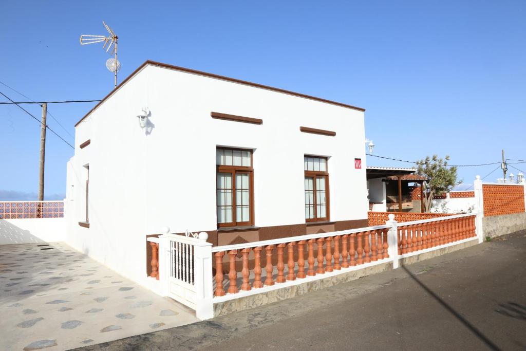 una casa blanca con una valla roja delante de ella en Casa El Molino en Puntallana