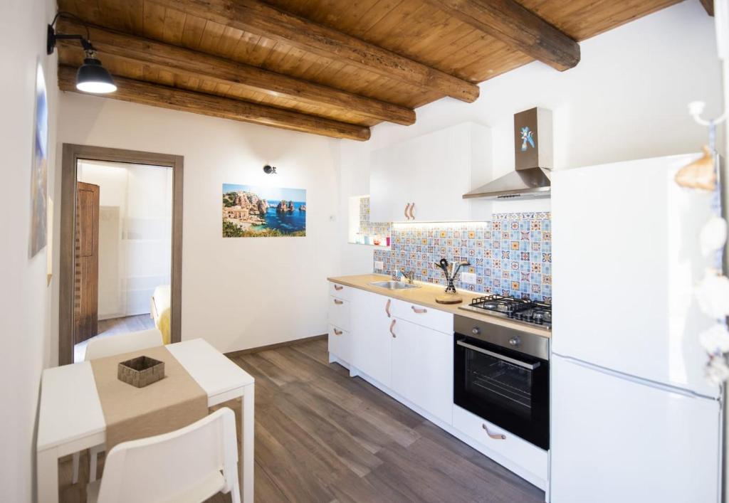 uma cozinha com armários brancos e um forno com placa de fogão em Casa vacanza oscar em Castellammare del Golfo