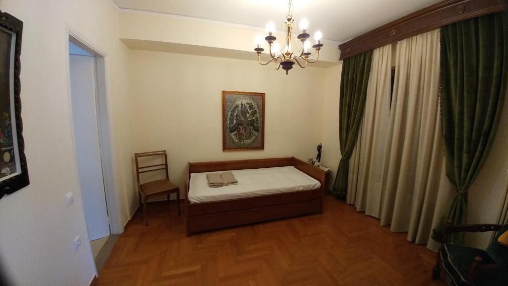 sypialnia z łóżkiem i żyrandolem w obiekcie Proteus Apartment w Atenach