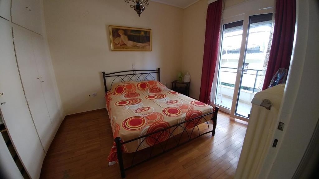 a bedroom with a bed with a flowered comforter and a window at Proteus Apartment in Athens