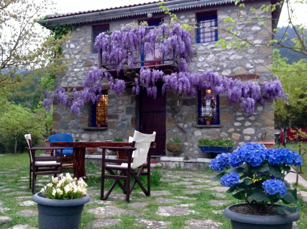 une maison avec une table et des fleurs violettes devant elle dans l'établissement Marina's Stone Cottage, à Ktistádes