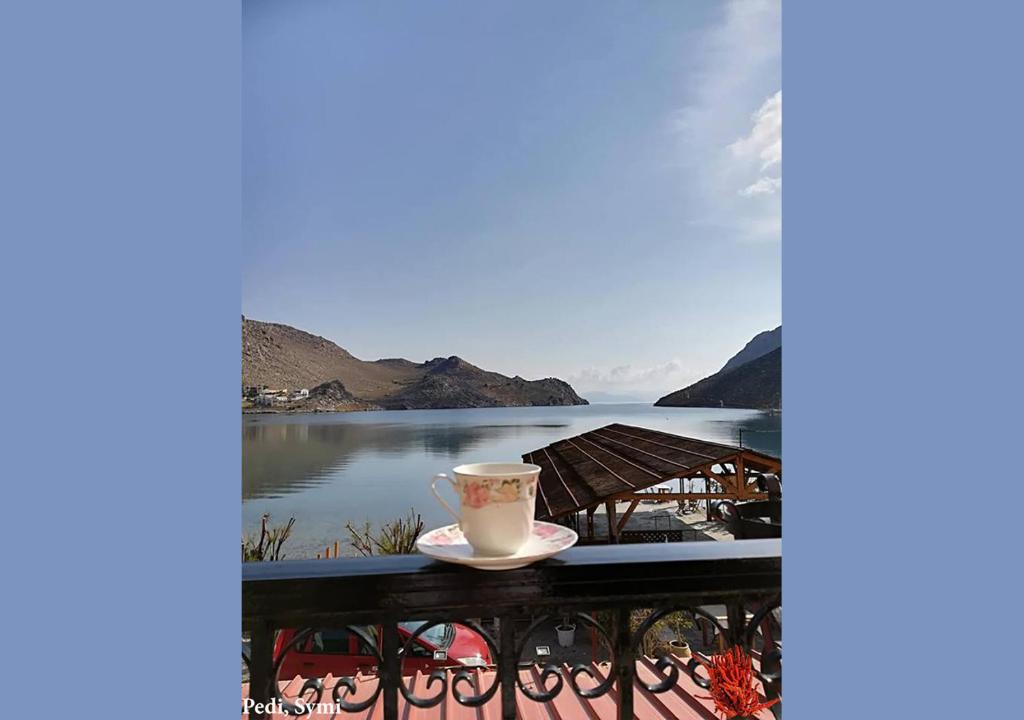 una tazza di caffè seduta su un balcone con vista sul lago di Korali a Sými