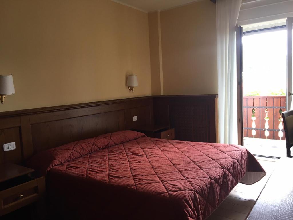 a bedroom with a bed with a red comforter and a window at Hotel Sporting in Roccaraso