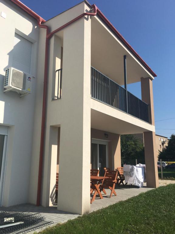 - un bâtiment blanc avec des chaises et un balcon dans l'établissement Szofi Apartman Pápa Fenyves u. 19., à Pápa