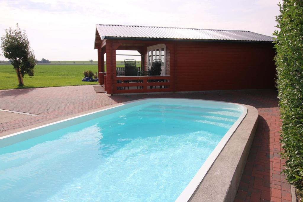 a swimming pool in front of a red building at Landhaus Nordsee-Peerhuus in Friedrichskoog