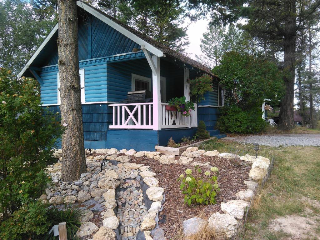 Fairmont Mountain Bungalows في فيرمونت هوت سبرينغز: منزل أزرق مع شرفة وحديقة صخرية