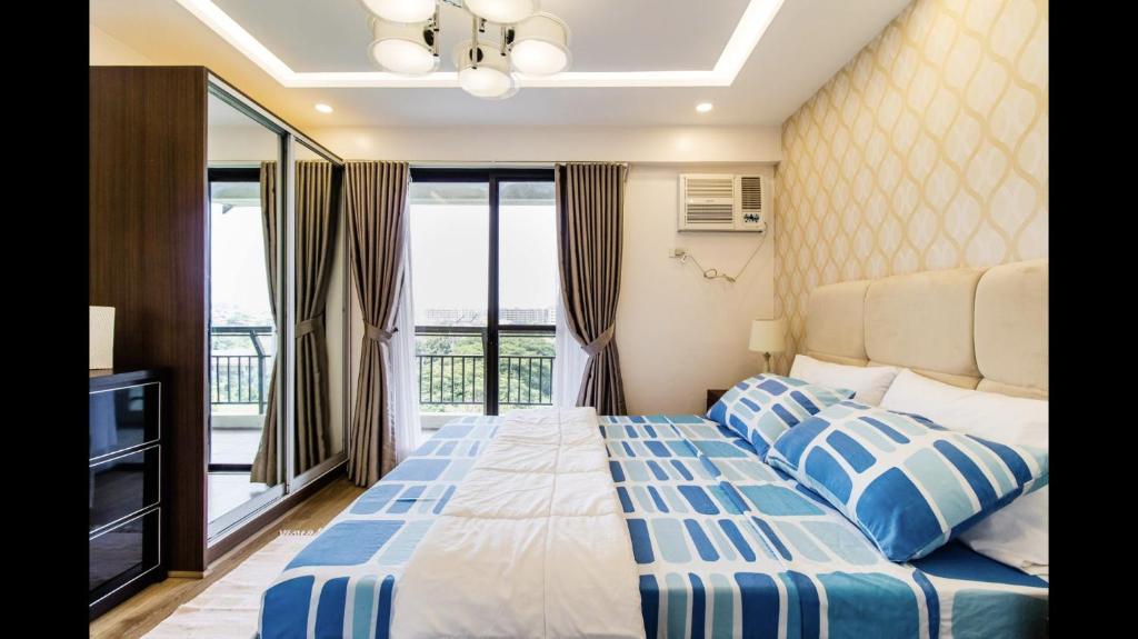マニラにあるGrand Apartment near BGCのベッドルーム(ベッド1台付)、バルコニーが備わります。