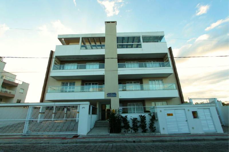 un gran edificio blanco con una valla delante en Edificio Villa Milano en Bombinhas