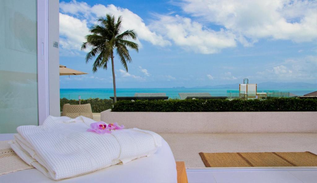 a bedroom with a bed and a view of the ocean at Code Samui Hotel in Mae Nam