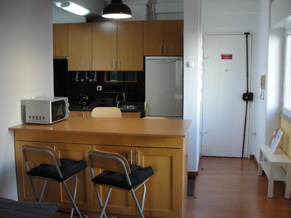 a kitchen with a counter with chairs and a microwave at Comfort City Hub - Metro Lisbon in Amadora