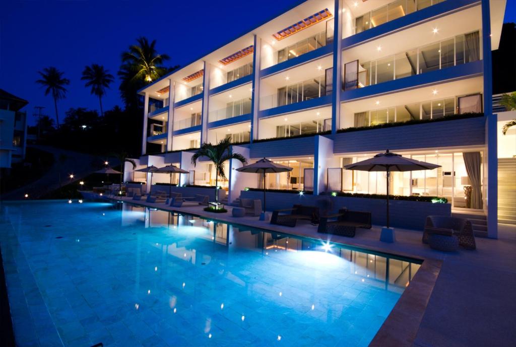 a swimming pool in front of a hotel at night at Code Samui Hotel in Mae Nam
