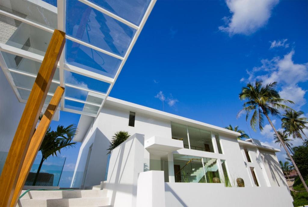 a glass facade of a house with palm trees at Code Samui Hotel in Mae Nam