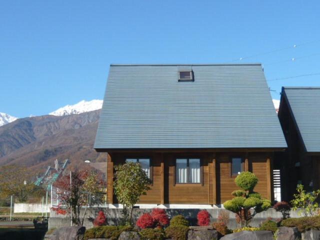 una casa de madera con una montaña en el fondo en Hakuba Happo Log Chalets, en Hakuba