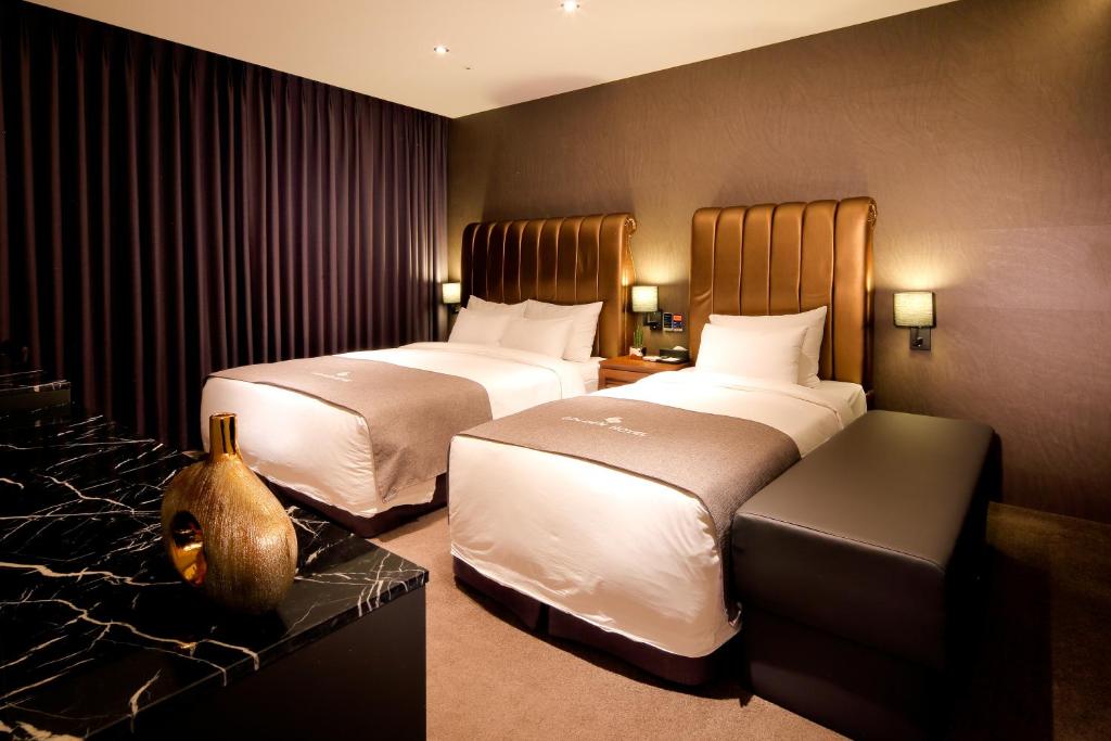 une chambre d'hôtel avec deux lits et un canapé dans l'établissement Golden Business Hotel, à Jinju