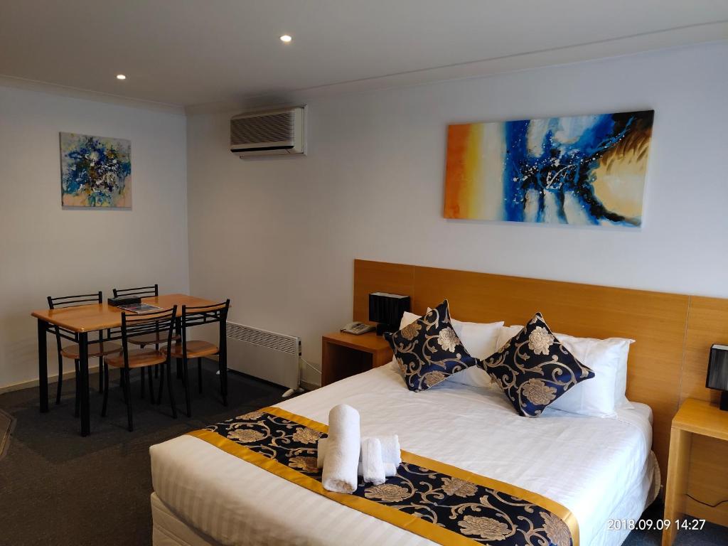 a hotel room with a bed and a table at Coachman Motel and Holiday Units in Cowes