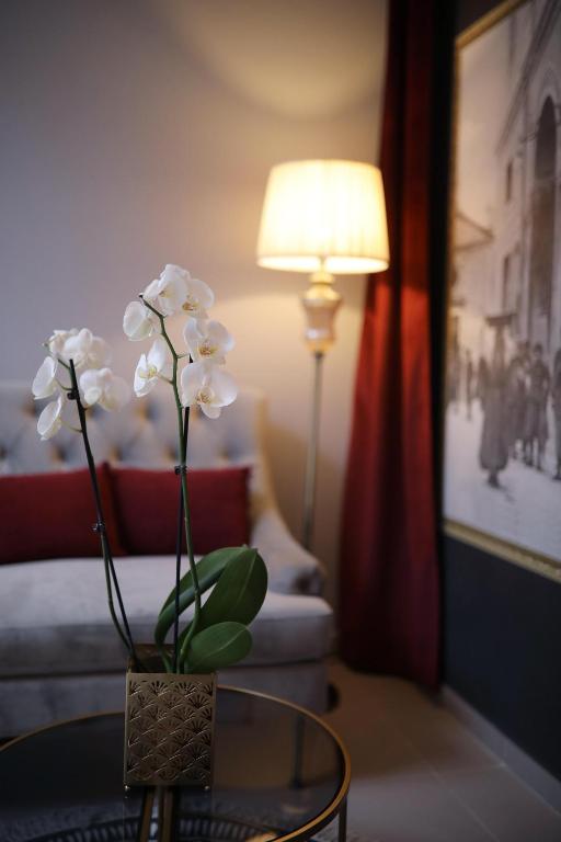 un jarrón de flores blancas sobre una mesa en una habitación en Teatro Verdi Boutique Hotel, en Zadar