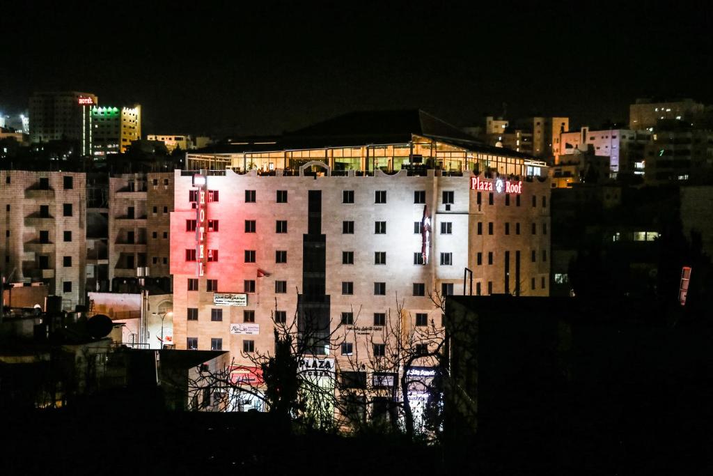 a lit up building in a city at night at Queen Plaza Hotel in Hebron