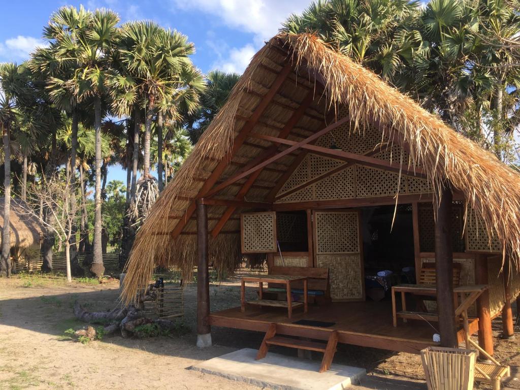 a hut with a straw roof with palm trees at Beach Hut by S.A.R. in Waingapu