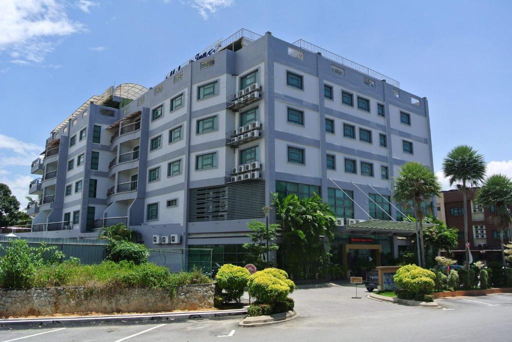 een groot wit gebouw met planten op een parkeerplaats bij Melang Inn in Kuala Pilah