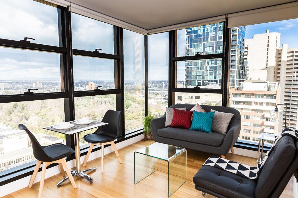 a living room with a couch and chairs and large windows at Executive stay Little Collins street in Melbourne