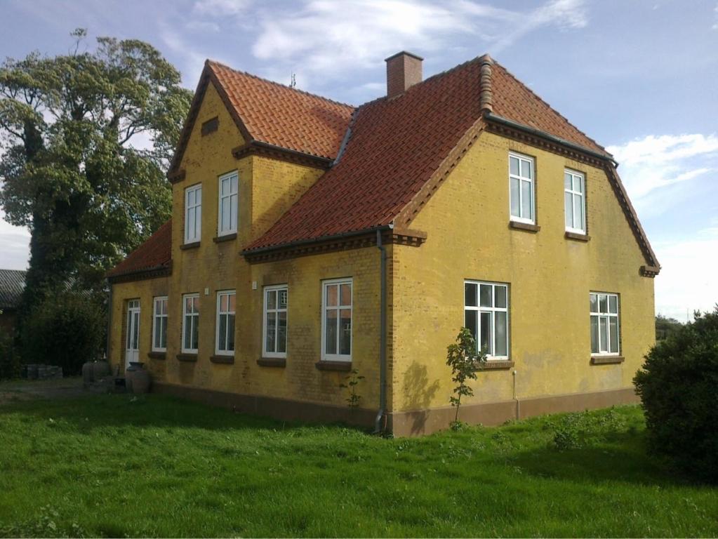 een geel huis met een rood dak op een veld bij A Big Holidayhouse Rømø-Rim-Ribe in Skærbæk