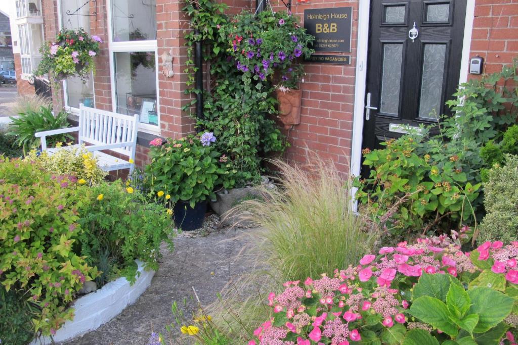 a garden with flowers and a bench in front of a house at Holmleigh House Bed and Breakfast in Seaton