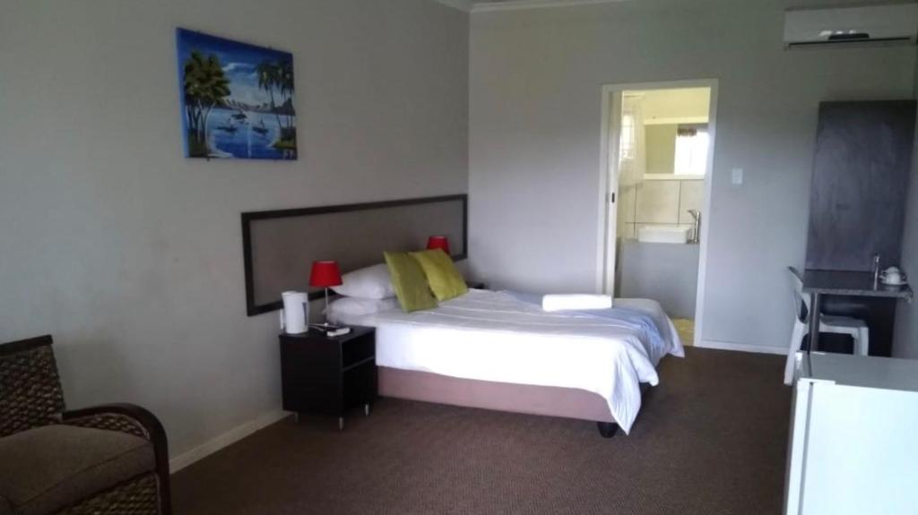 a bedroom with a bed and a table and a chair at Amble Inn Guest House in Empangeni