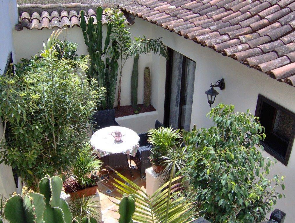 un jardín con una mesa y algunas plantas en Apartamentos-Monasterio-de-San-Antonio-Rustikales-Apartment-mit-kleiner-Terrasse-im-Innenhof, en Icod de los Vinos