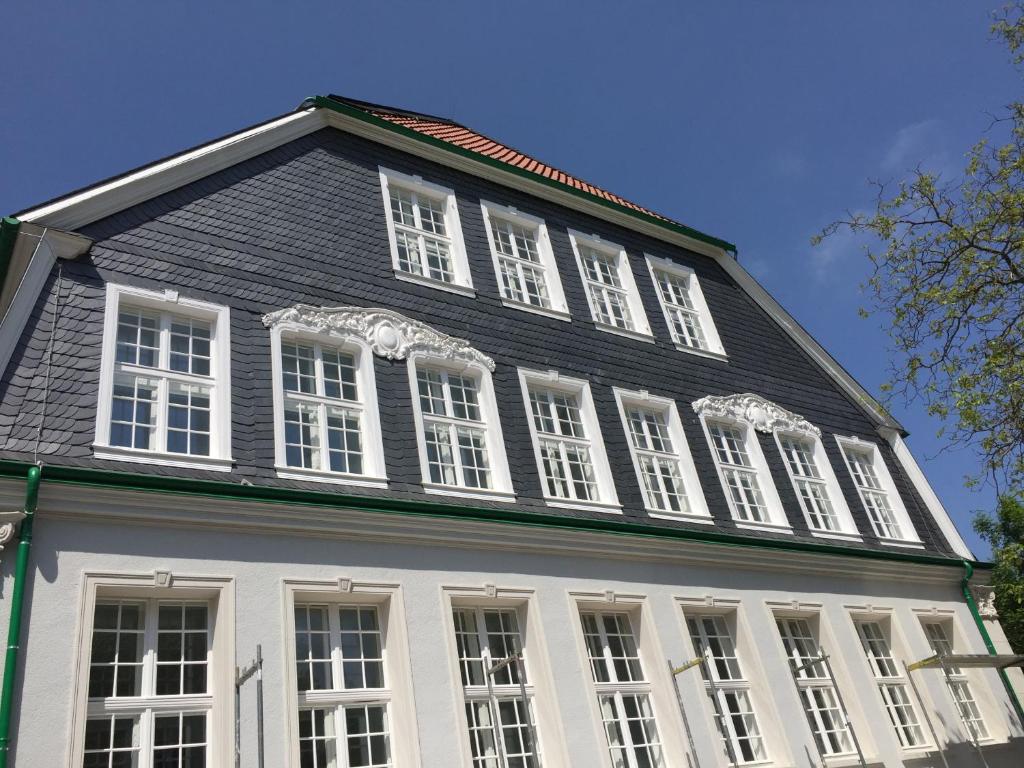 a large black and white house with white windows at Schulhaus Hotel in Schwelm