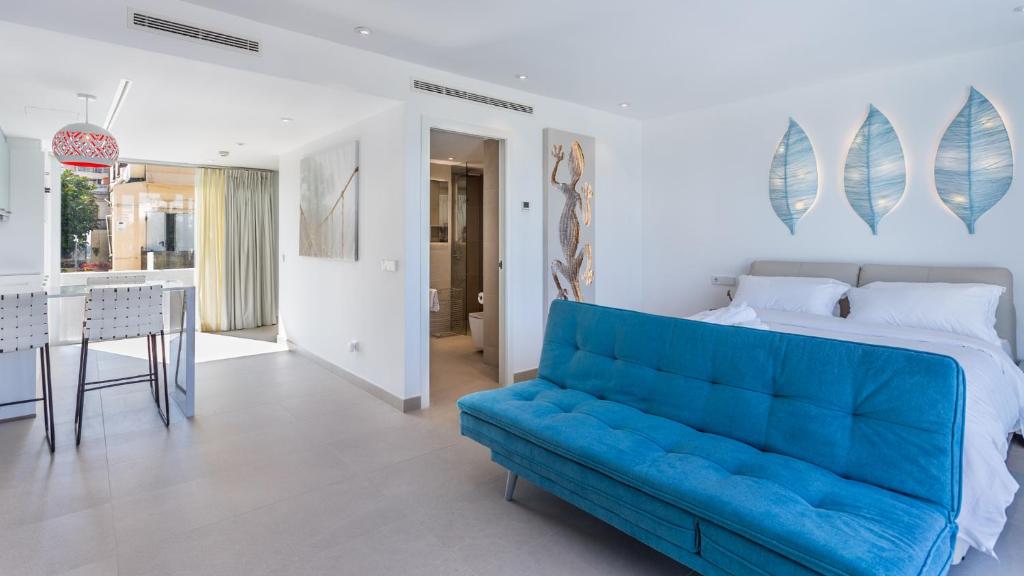 a blue couch in a white room with a bed at The Hype Beachhouse in Playa de Palma