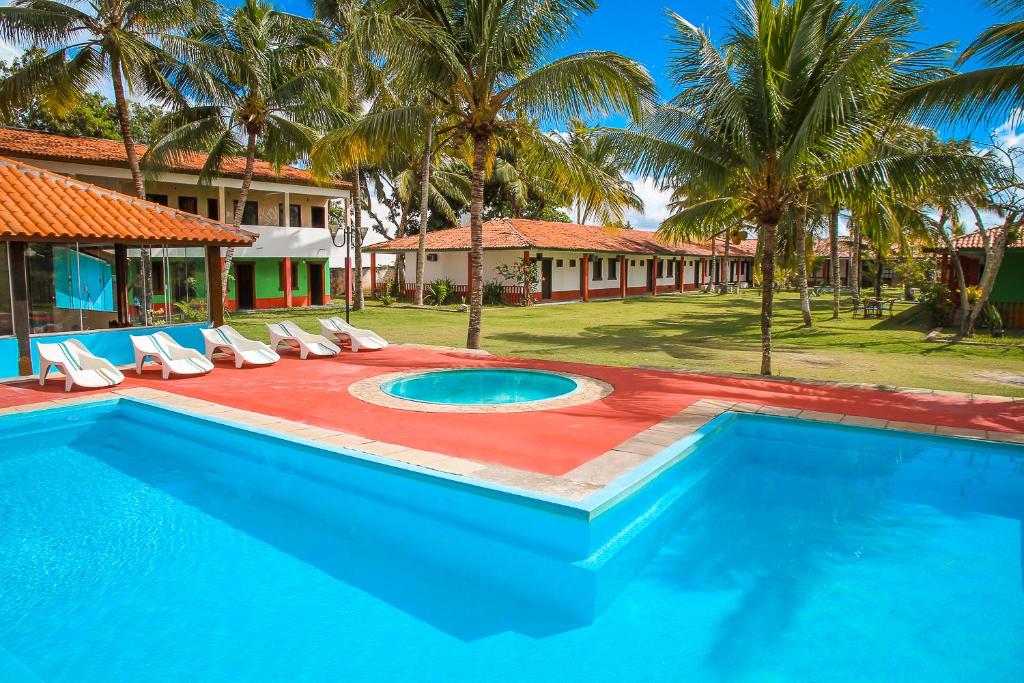 a swimming pool with chairs and a resort at Pousada Morada dos Coqueiros in Porto Seguro