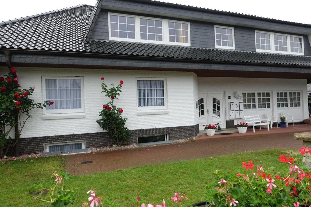 a white house with red flowers in the yard at Möwe in Kappeln