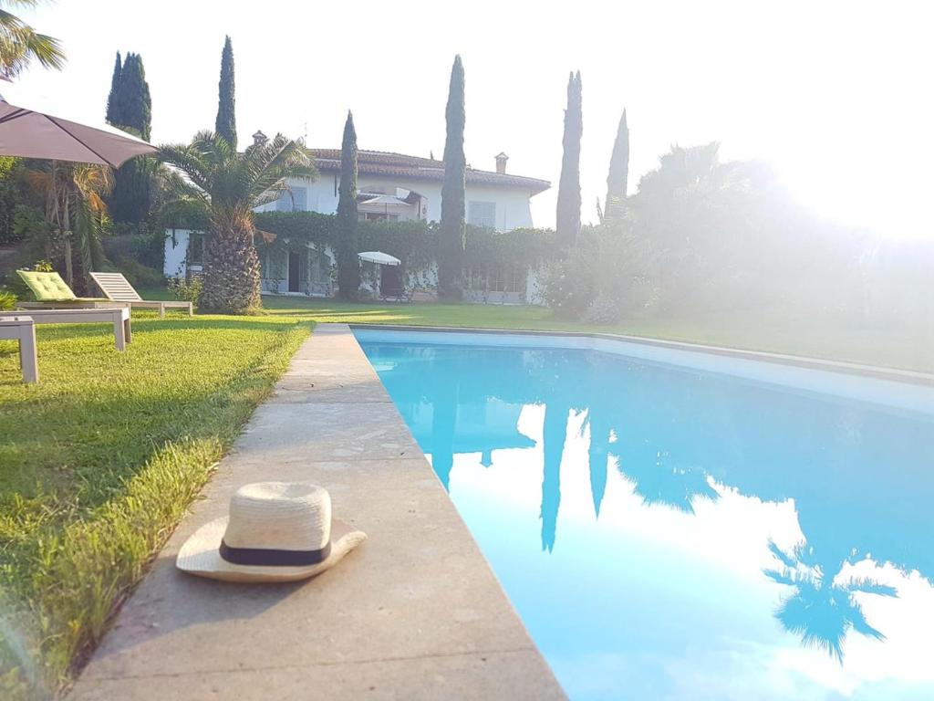 un sombrero sentado al lado de una piscina en Villa Romana, en Campagnano di Roma