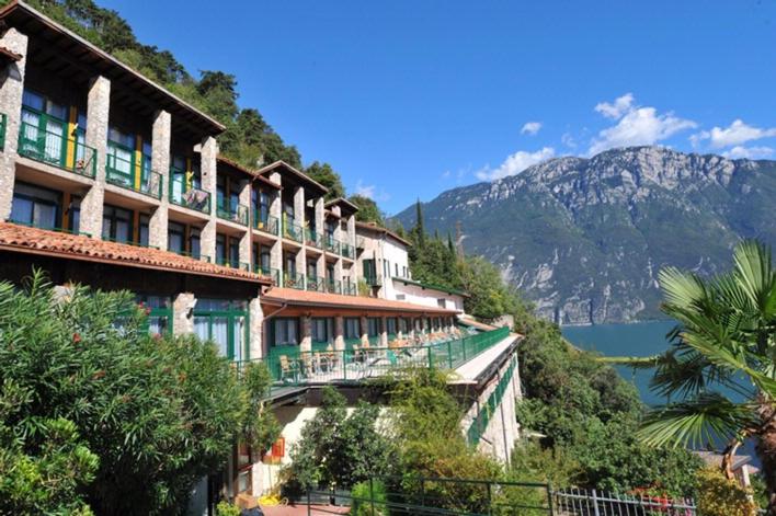 un bâtiment sur le flanc d'une montagne avec un lac dans l'établissement Centro Vacanze La Limonaia, à Limone sul Garda