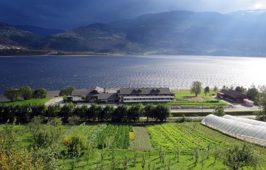 une grande maison dans un champ à côté d'un lac dans l'établissement Voss Vandrarheim Hostel, à Vossevangen