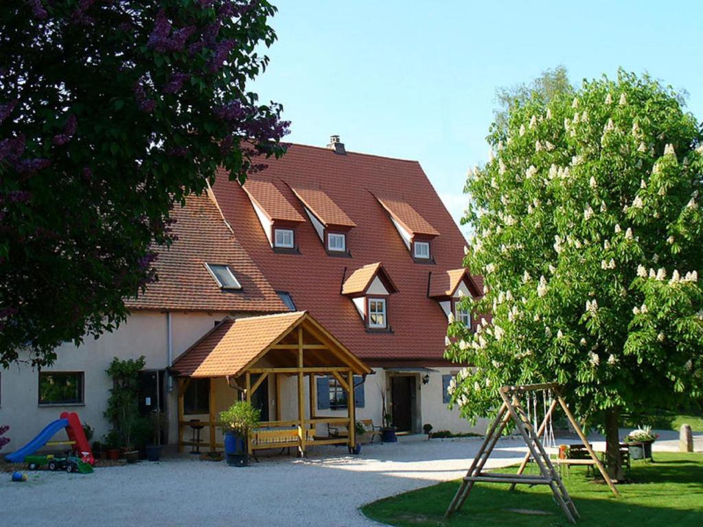 ein großes Haus mit einem Spielplatz davor in der Unterkunft Bio-Ferienhof Scheckenbauer in Höttingen