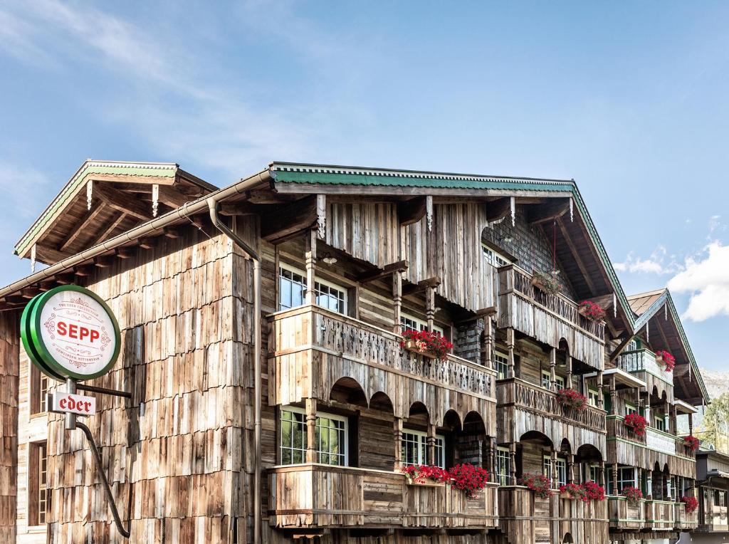 un vieux bâtiment en bois avec des fleurs sur les balcons dans l'établissement HOTEL SEPP - Alpine Boutique Hotel - Adults Only, à Maria Alm