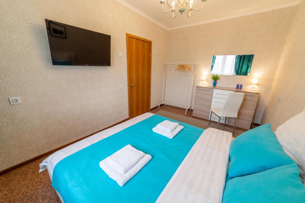 Schlafzimmer mit einem blauen Bett und einem Flachbild-TV in der Unterkunft Five Stars Grand Style in Krasnojarsk