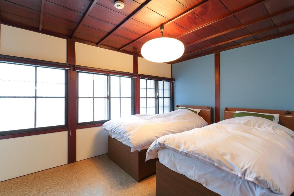 twee bedden in een kamer met ramen bij Higashiyama Chitaru in Kanazawa in Kanazawa