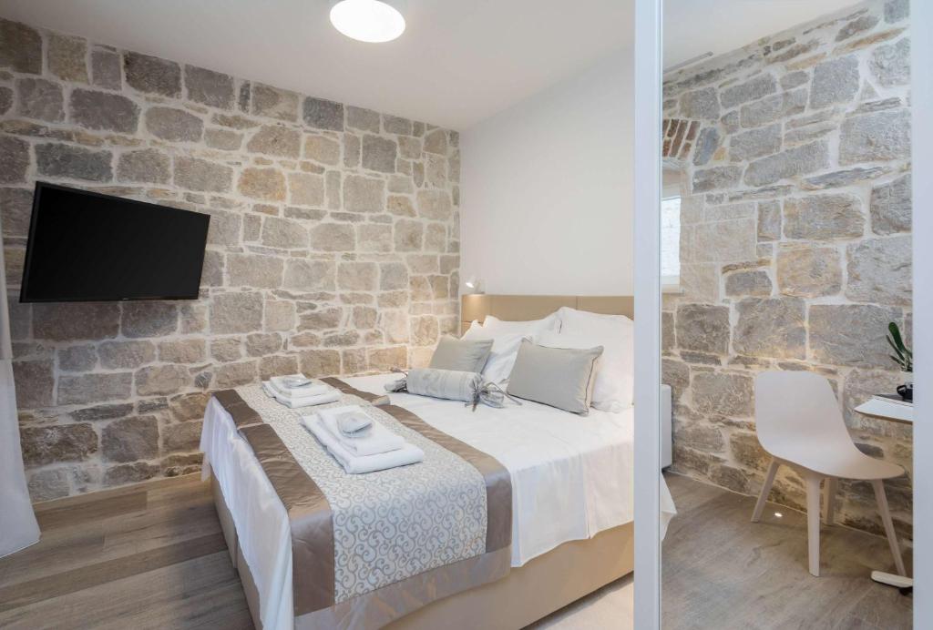 a bedroom with a bed and a stone wall at Mediterra Residence in Split