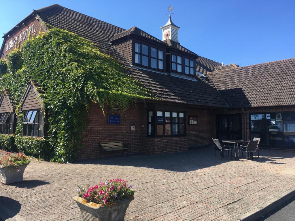 un edificio cubierto de hiedra con mesa y sillas en The Abbey Hotel and conference centre en Minster