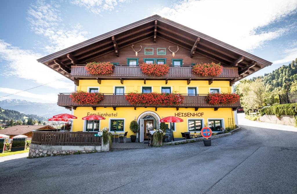 ein gelbes Gebäude mit roten Sonnenschirmen davor in der Unterkunft Hotel Apart Garni Heisenhof in Westendorf