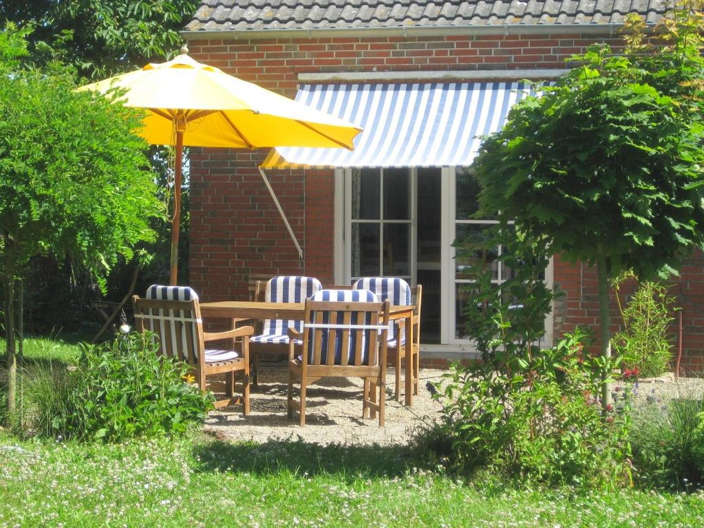 a table and chairs under an umbrella in a yard at Campen Cottage in Krummhörn