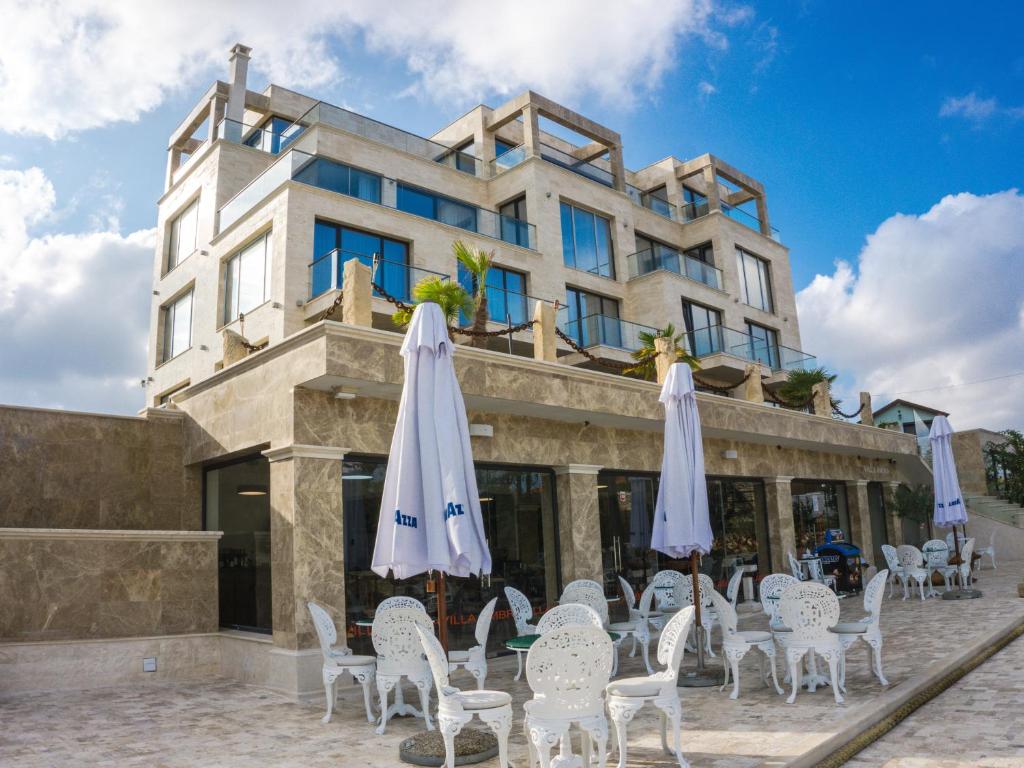 a building with chairs and umbrellas in front of it at Villa Ambra in Tyulenovo