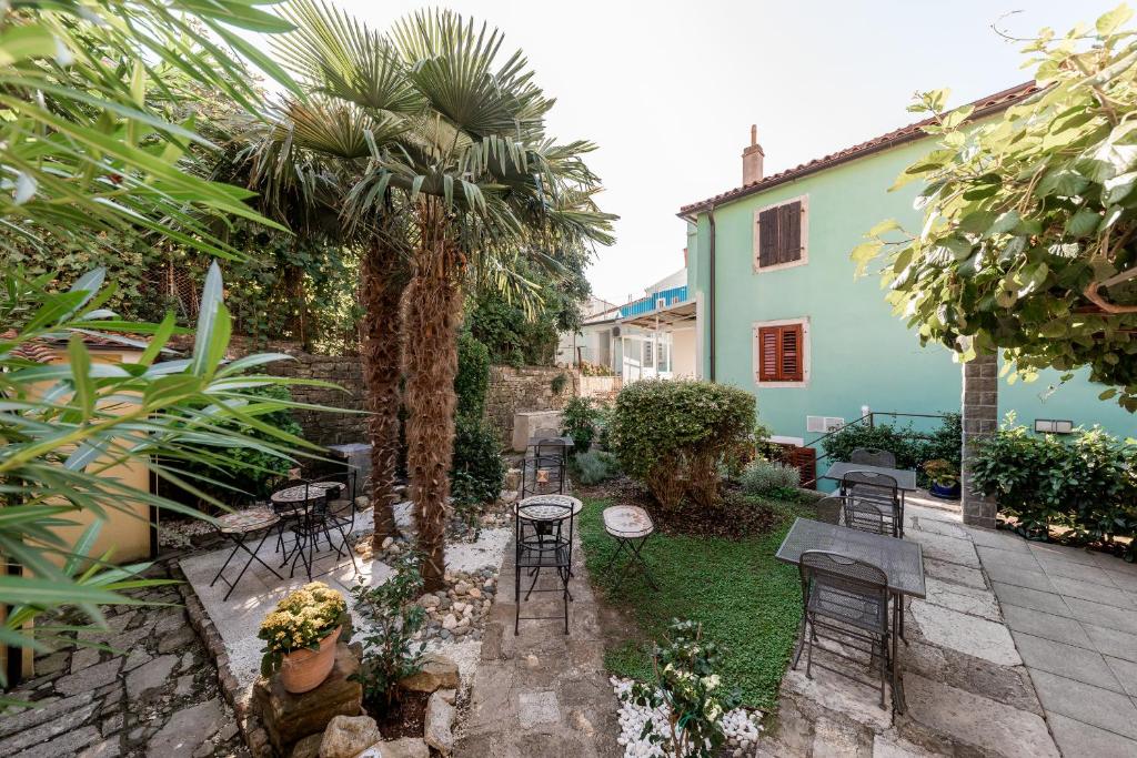 a patio with tables and chairs and a palm tree at Miracolo di Mare Retro in Piran