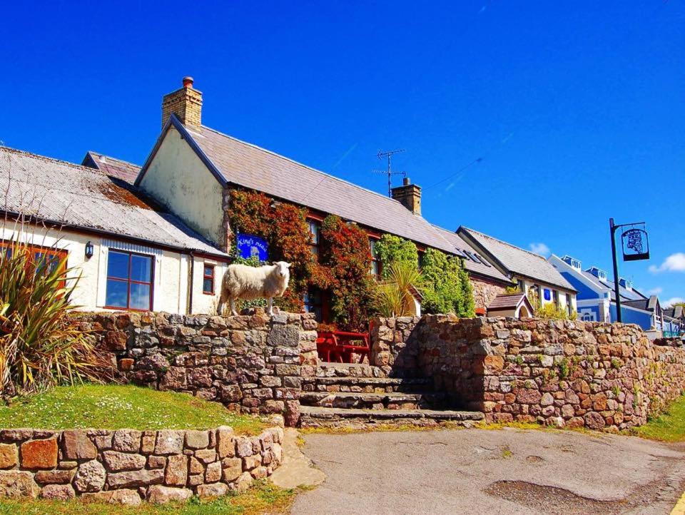 a house with a goat standing on a stone wall at King's Head Inn in Llangennith